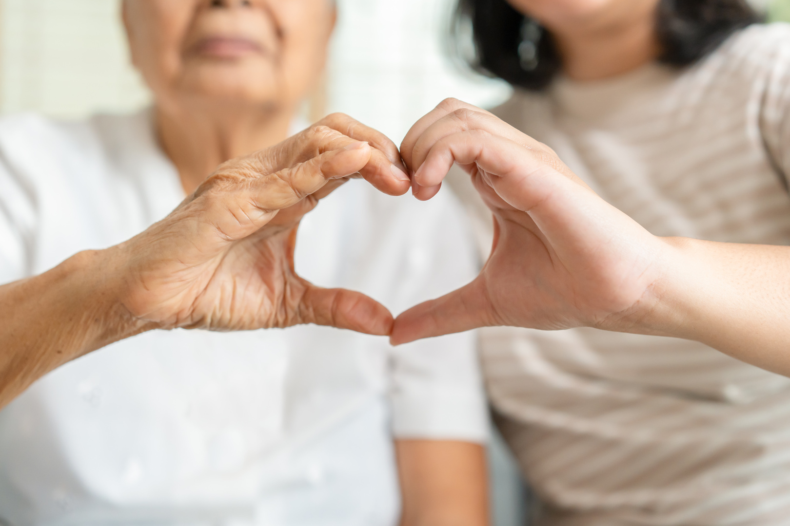 Young and senior woman doing heart sign