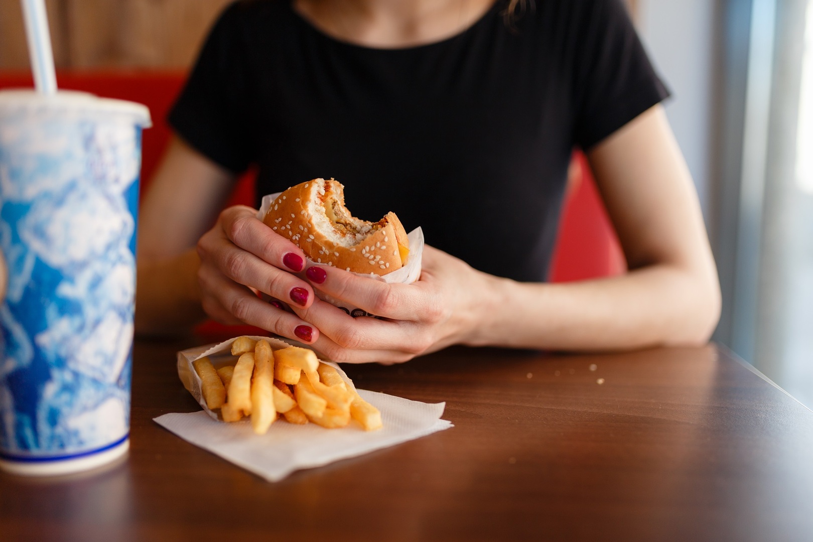 Young girl holding in female hands fast food burger